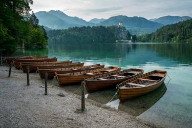 Rowboats and secluded shingle shoreline along Mlino Bay at Lake Bled